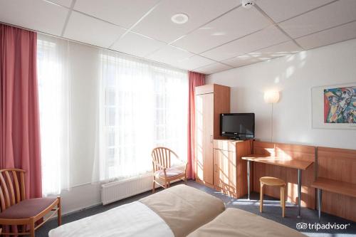 a hotel room with a bed and a desk and a television at Rho Hotel in Amsterdam