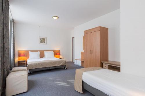 a hotel room with two beds and a cabinet at Rho Hotel in Amsterdam