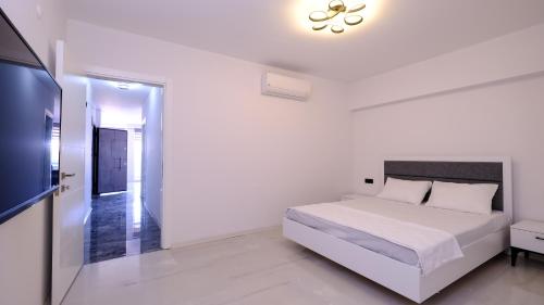 a white bedroom with a bed and a flat screen tv at Oksa Apart in Kusadası