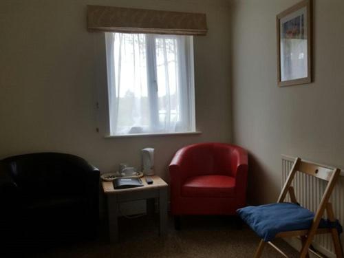 阿克斯敏斯特的住宿－A35休息站客房汽車旅館，客厅配有红色椅子和窗户