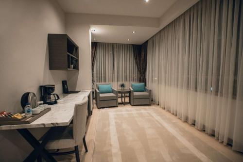 a living room with two chairs and a table and curtains at Hilly Hotel in Edirne