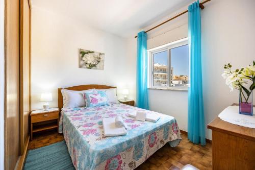 een slaapkamer met een bed met blauwe gordijnen en een raam bij Villas Brites nº4 in Burgau