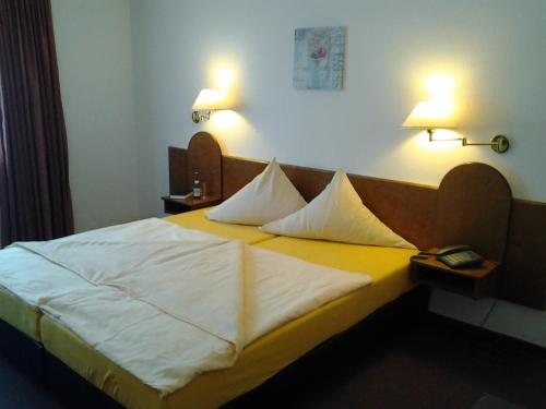 ein Schlafzimmer mit einem Bett mit weißer Bettwäsche und zwei Lampen in der Unterkunft Heidehotel Herrenbrücke in Faßberg