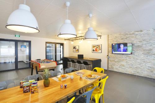 une salle à manger avec une table et une télévision sur un mur en briques dans l'établissement Résidence Nemea Aix Campus 2, à Aix-en-Provence