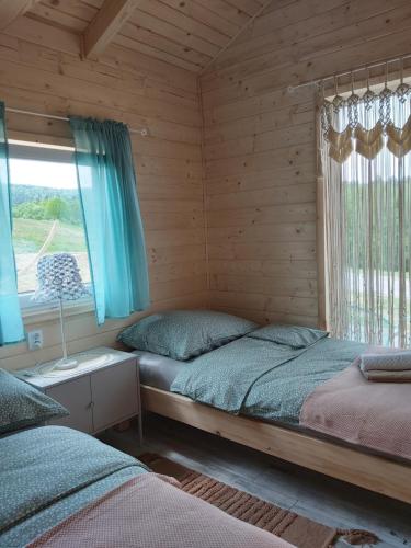 2 camas en una cabaña de madera con ventana en Domek Polna Cisza Bieszczady en Lesko