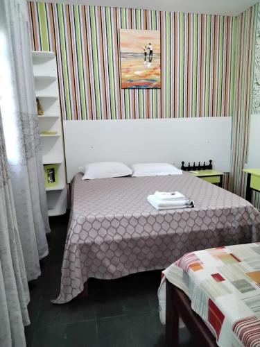 a bedroom with a bed and a striped wall at Suíte 06 Exclusiva e Independente in Cuiabá