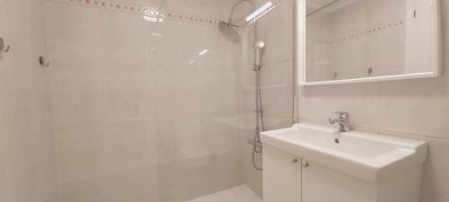 uma casa de banho branca com um chuveiro e um lavatório. em Valdenoja-Sardinero Apartment Suite Beach em Santander
