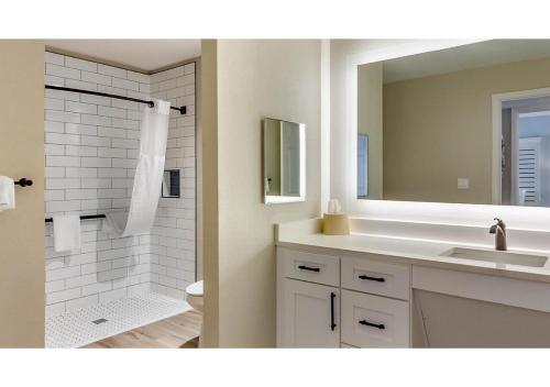a bathroom with a sink and a toilet and a mirror at Via Roma Beach Resort in Bradenton Beach