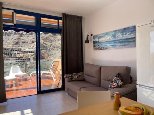 een woonkamer met een bank en een balkon bij Apartment with views of sea and mountains in Taurito