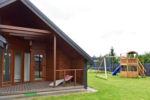 a small house with a playground and a slide at Kotedžai GULBĖS TAKAS Šventojoje in Šventoji