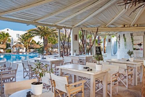 Un restaurante con mesas y sillas y una piscina. en Atlantis Beach Villa, en Perivolos