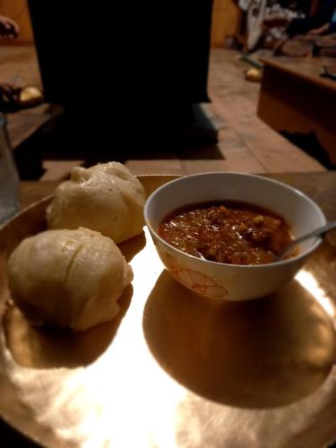 a bowl of soup and two rolls on a table at Lahaul Home Stay Sumnam in Tāndi