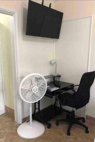 a desk with a fan and a chair in a room at Kelly's Studio Apartment - Rental near Airport, Amenities and Bus Route in Saint Philip