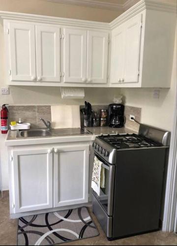 a kitchen with a black stove and white cabinets at Kelly's Studio Apartment - Rental near Airport, Amenities and Bus Route in Saint Philip