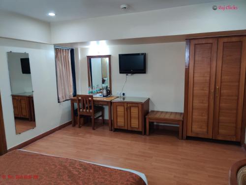 a hotel room with a desk and a television at Hotel Abigail Regency in Shirdi