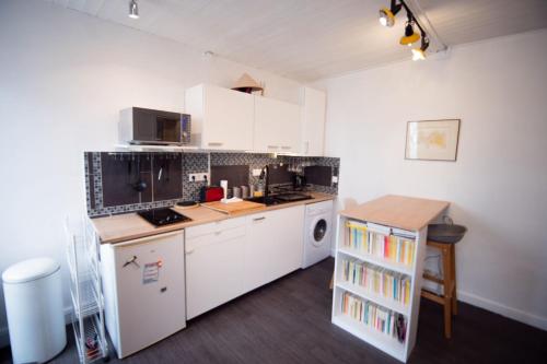 une petite cuisine avec des armoires blanches et une table dans l'établissement Cozy 1 Bedroom Apartment In 14th, à Paris