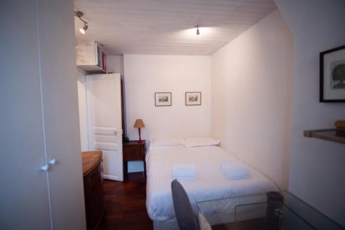 パリにあるCozy 1 Bedroom Apartment In 14thの白い小さなベッドルーム(ベッド1台、椅子付)