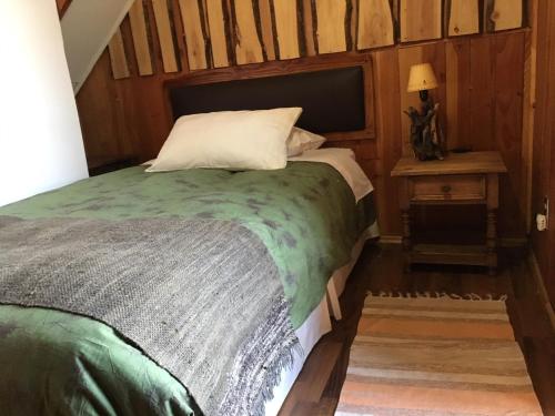 a bedroom with a bed and a table with a lamp at B&B HMüller in Pucón