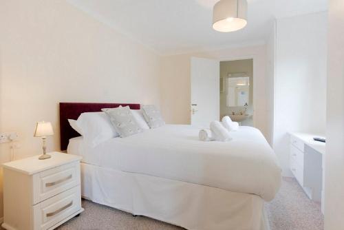 a white bedroom with a large white bed and a sink at Newby Bridge Country Caravan Park in Newby Bridge