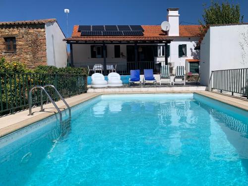 a swimming pool with blue chairs and a house at Casa Agostinho - with private pool near Coimbra in Graça