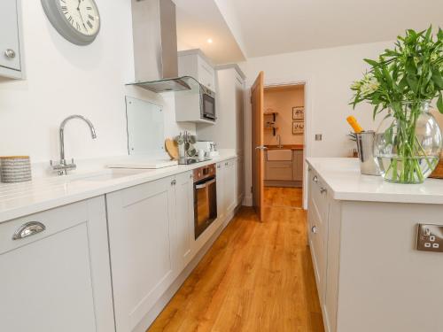 a kitchen with white cabinets and a wooden floor at Pen Bryn in Ruthin