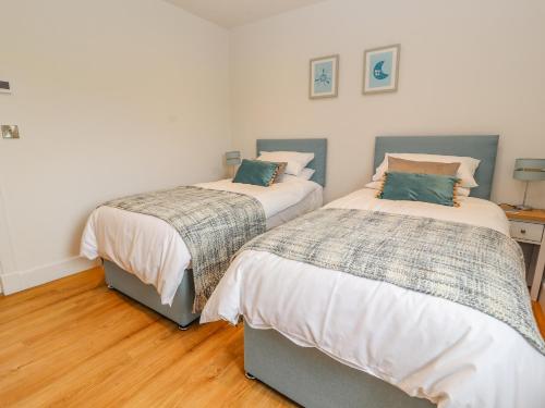 two beds in a room with wood floors at Pen Bryn in Ruthin