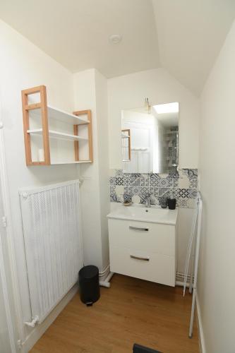 biała łazienka z umywalką i lustrem w obiekcie L'Ango appartement triplex vue port w mieście Dieppe