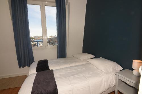 sypialnia z białym łóżkiem i oknem w obiekcie L'Ango appartement triplex vue port w mieście Dieppe