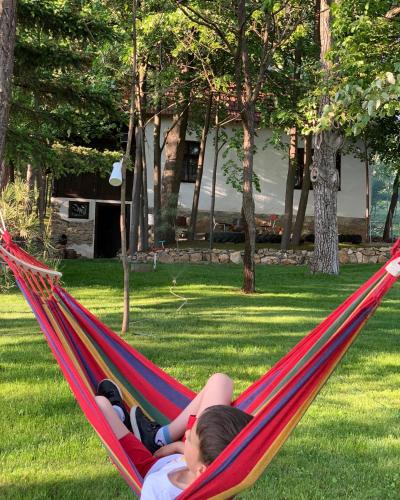 a child laying in a hammock in a yard at Konaciste Mali Izvor in Boljevac