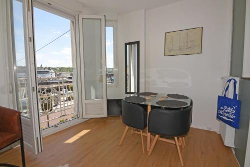 une salle à manger avec une table et des chaises et un balcon dans l'établissement L'Ango appartement triplex vue port, à Dieppe