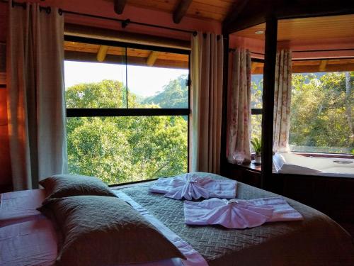 a bed in a room with a large window at Pousada Mirante do Céu in Visconde De Maua