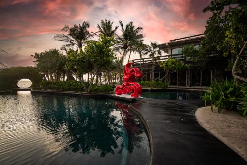 a pool with a red statue in front of a house at Casa Malca in Tulum