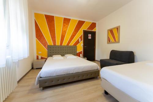 a hotel room with two beds and a chair at MH Hotel Benaco in Peschiera del Garda