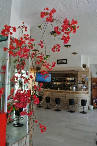 a bunch of red flowers in a room with a bar at Kokalakis Hotel in Kefalos