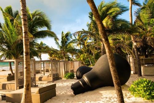 a sculpture on the beach next to palm trees at Casa Malca in Tulum