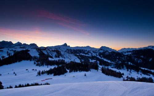 a group of people skiing down a snow covered mountain at Hotel Miramonti Corvara in Corvara in Badia
