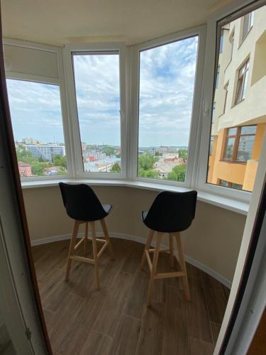 two chairs in a room with three windows at Нові апартаменти по вулиці Роксолани16 in Truskavets