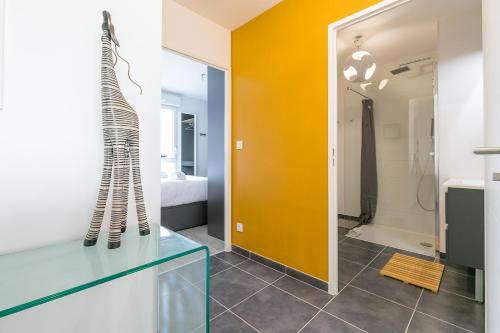 uma casa de banho com um armário de vidro e uma parede amarela em Le Fantasy em Dijon