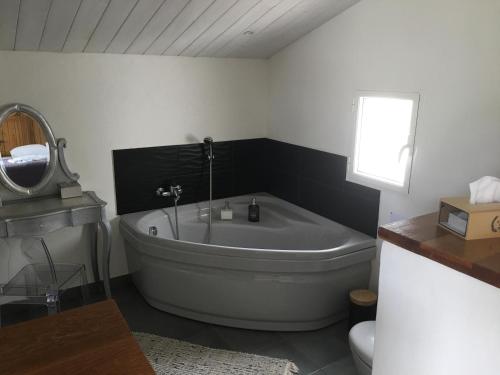 ein Badezimmer mit einer Badewanne, einem Waschbecken und einem Spiegel in der Unterkunft chambre d hôtes les trois châteaux piscine intérieure chauffée in Notre-Dame-de-Riez