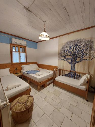 a room with two beds and a tree mural on the wall at Mavilia Traditional Guesthouse in Ligourio