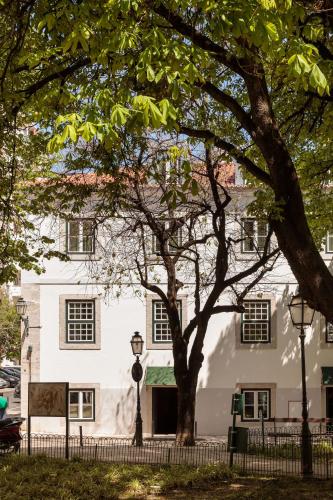 a white building with a tree in front of it at Hotel das Amoreiras - Small Luxury Hotels of the World in Lisbon