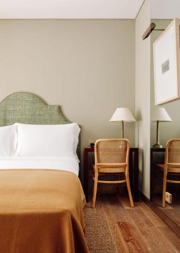 a bedroom with a bed and two chairs and a lamp at Hotel das Amoreiras - Small Luxury Hotels of the World in Lisbon