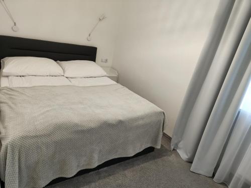 1 dormitorio con 1 cama con sábanas blancas y ventana en Perełka (by F&J), en Toruń
