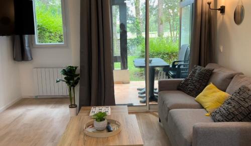 ein Wohnzimmer mit einem Sofa und einem Tisch in der Unterkunft LE COSY Résidence du Golf in Deauville
