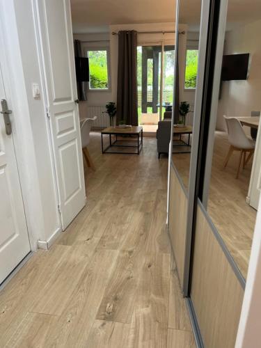 een woonkamer met een houten vloer en een spiegel bij LE COSY Résidence du Golf in Deauville