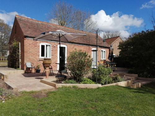 a small brick house with an umbrella in the yard at Risley Guest House in Risley