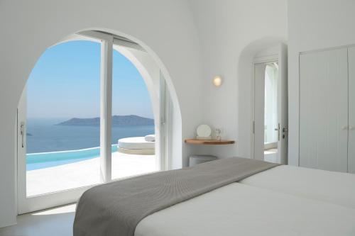 a bedroom with a bed and a view of the ocean at Villa Dio - An Iconic Villa Above Caldera in Firostefani