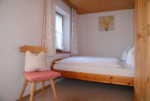 ein kleines Schlafzimmer mit einem Bett und einem Stuhl in der Unterkunft Haus Mitterstang in Bischofswiesen