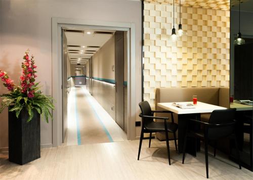 a dining room with a table and chairs and a hallway at Hotel Lombardia in Milan