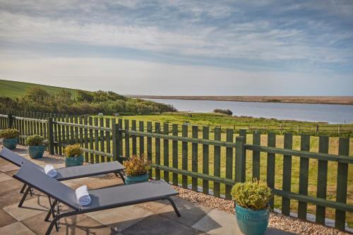 a patio with two benches and a fence and water at Moonfleet Manor Hotel in Weymouth